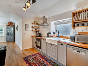 Una cucina moderna con mobili in legno, forno integrato, microonde e una finestra con persiane.