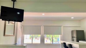 A modern kitchen with a flat-screen TV, large windows, and a bar area. - Studio apartment on 5th Avenue, just steps from the beach, the ferry, ADO buses, parks, and more (Playa del Carmen)