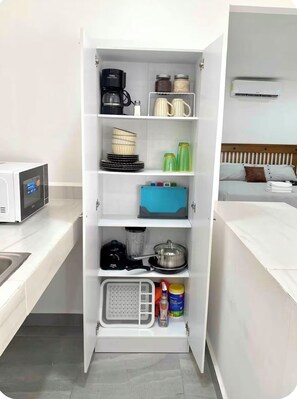 A compact kitchen with a microwave, coffee maker, and storage shelves. - Studio apartment on 5th Avenue, just steps from the beach, the ferry, ADO buses, parks, and more (Playa del Carmen)