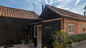 En bygning med sort facade, et skilt der viser 'OSTLER'S LODGE', og en grusvej.
