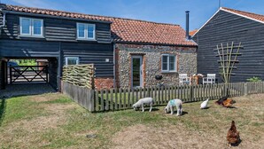 En landejendom med stenvæg, træhegn og en klar himmel.
