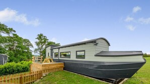 Ett flytande hus med ett däck, en liten sittplats utomhus och ett fönster.
