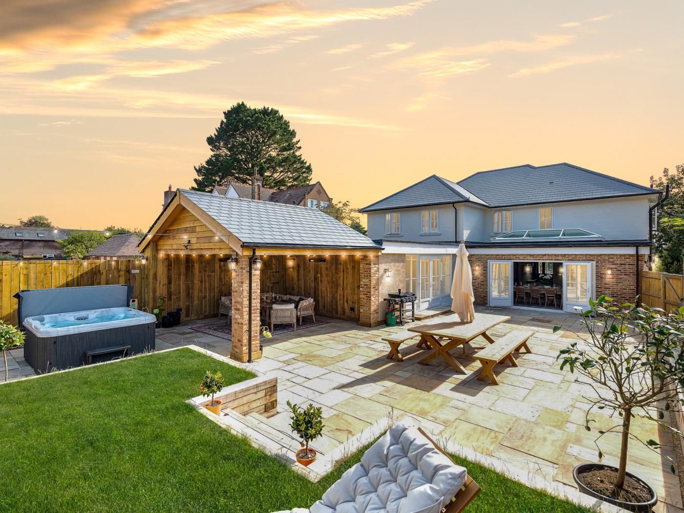 A backyard with a hot tub, outdoor seating, and a barbecue area.