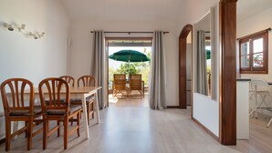Una zona pranzo con sedie e tavolo in legno, una cucina con una finestra e vista sull'esterno.
