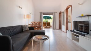 Un soggiorno moderno con divano, tavolino, televisione e zona pranzo con sedie e tavolo.