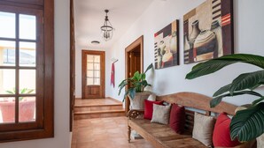 Un pasillo con un banco de madera, una escalera y un ventanal grande.