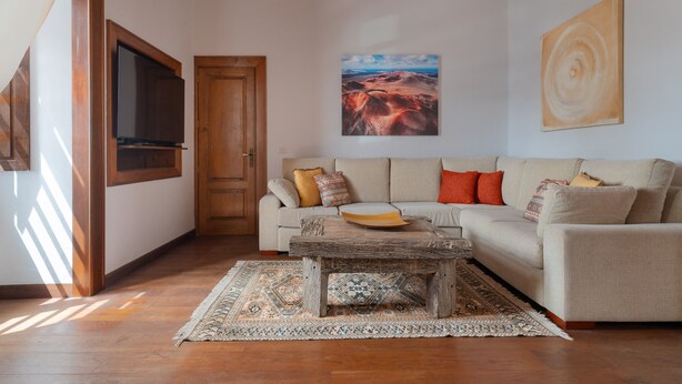Una sala de estar con un sofá, una mesa de centro, un televisor y un cuadro en la pared.