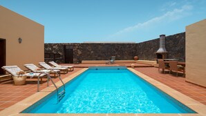Una piscina con sillas de descanso y un muro de piedra.