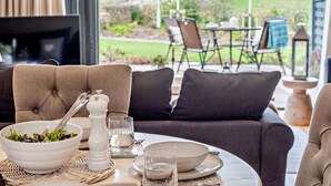 Een eetgedeelte met een tafel voor twee personen, een saladekom, een zout- en peperstel en een waterglas.