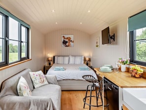 Une chambre confortable avec un lit, des tables de chevet, un bureau avec une chaise et une vue sur l’extérieur.