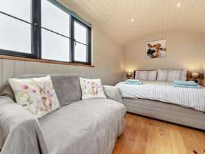 Ein gemütliches Schlafzimmer mit Sofa, einem Bett mit gestreifter Bettwäsche, einer Wandlampe und einem gerahmten Bild.