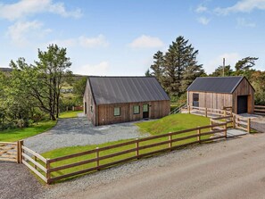 Une grange en bois avec une allée en gravier et une clôture en bois.