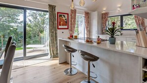 A modern kitchen with a bar area, large windows, and a view of the outdoors.