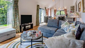 A modern living room with a sofa, a coffee table, a TV, and a dining area with chairs and a table.
