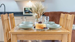 A dining table with chairs, a cake, and a vase with dried plants. - 1 Bed in South Molton (oc-96105) (South Molton)