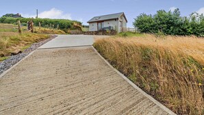 A rural property with a paved driveway leading to a house with a stone foundation and a sloped roof. - 1 Bed in South Molton (oc-96105) (South Molton)