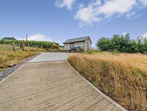 Ein ländliches Anwesen mit einem gepflasterten Weg, der zu einem Haus mit Stein Fundament und einem geneigten Dach führt.