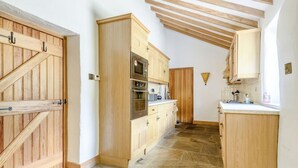 A kitchen with wooden cabinets, a stone floor, and a built-in oven. - 3 Bed in Buxton (oc-96211) (Cressbrook)