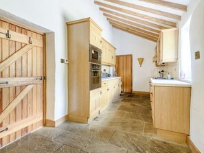 A kitchen with wooden cabinets, a stone floor, and a built-in oven. - 3 Bed in Buxton (oc-96211) (Cressbrook)