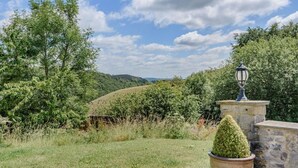 A stone structure with a lamp post, surrounded by greenery and a hill in the background. - 3 Bed in Buxton (oc-96211) (Cressbrook)