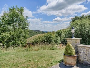 A stone structure with a lamp post, surrounded by greenery and a hill in the background. - 3 Bed in Buxton (oc-96211) (Cressbrook)