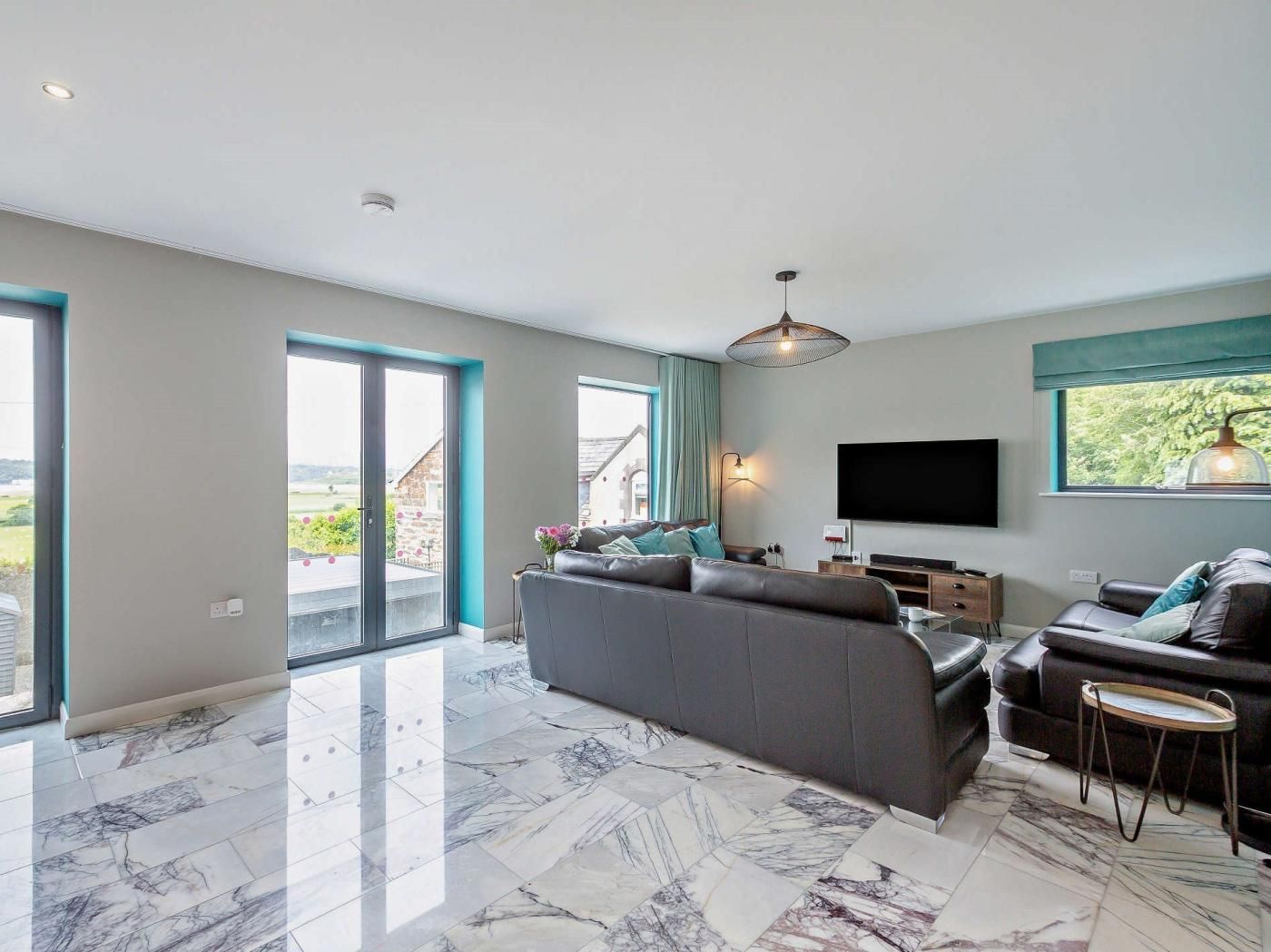 Een moderne woonkamer met een grote bank, een televisie en een balkon met uitzicht.