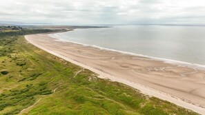 Eine Küstenlandschaft mit einem breiten Sandstrand und einer Rasenfläche.