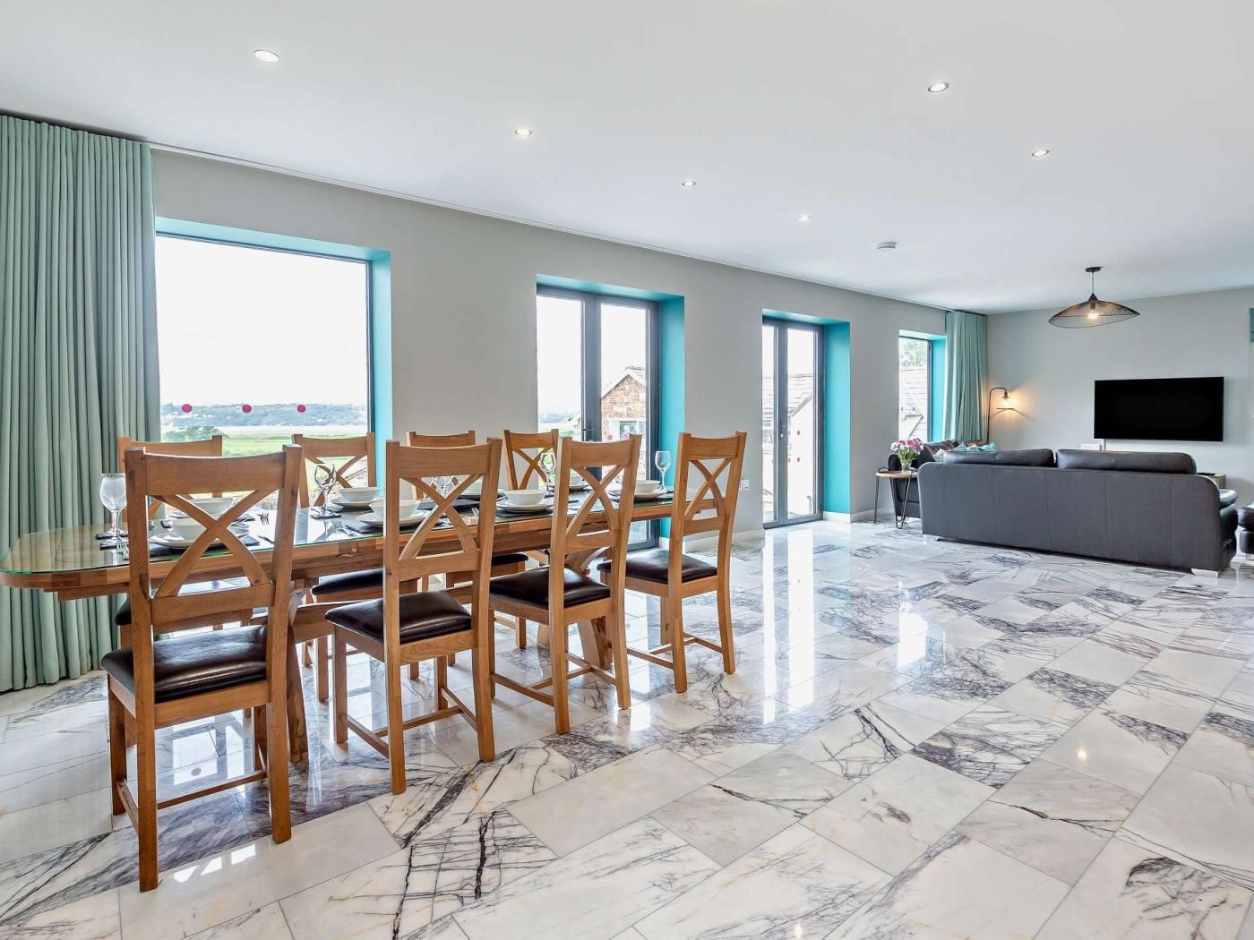 A spacious living area with a dining table, chairs, a sofa, and a TV.