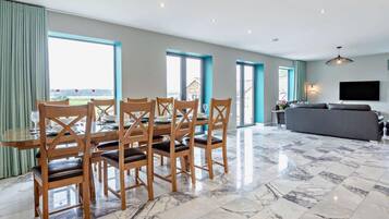 A spacious living area with a dining table, chairs, a sofa, and a TV.