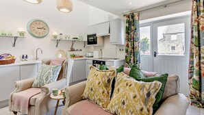 A cozy living room with a sofa, a small table, and a kitchen area with a microwave and cabinets. - 1 Bed in Gateshead (oc-95877) (Lamesley)