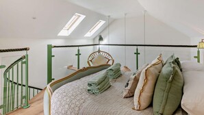 A bedroom with a bed, pillows, a hanging chair, a staircase with green railings, and skylights. - 1 Bed in Gateshead (oc-95877) (Lamesley)