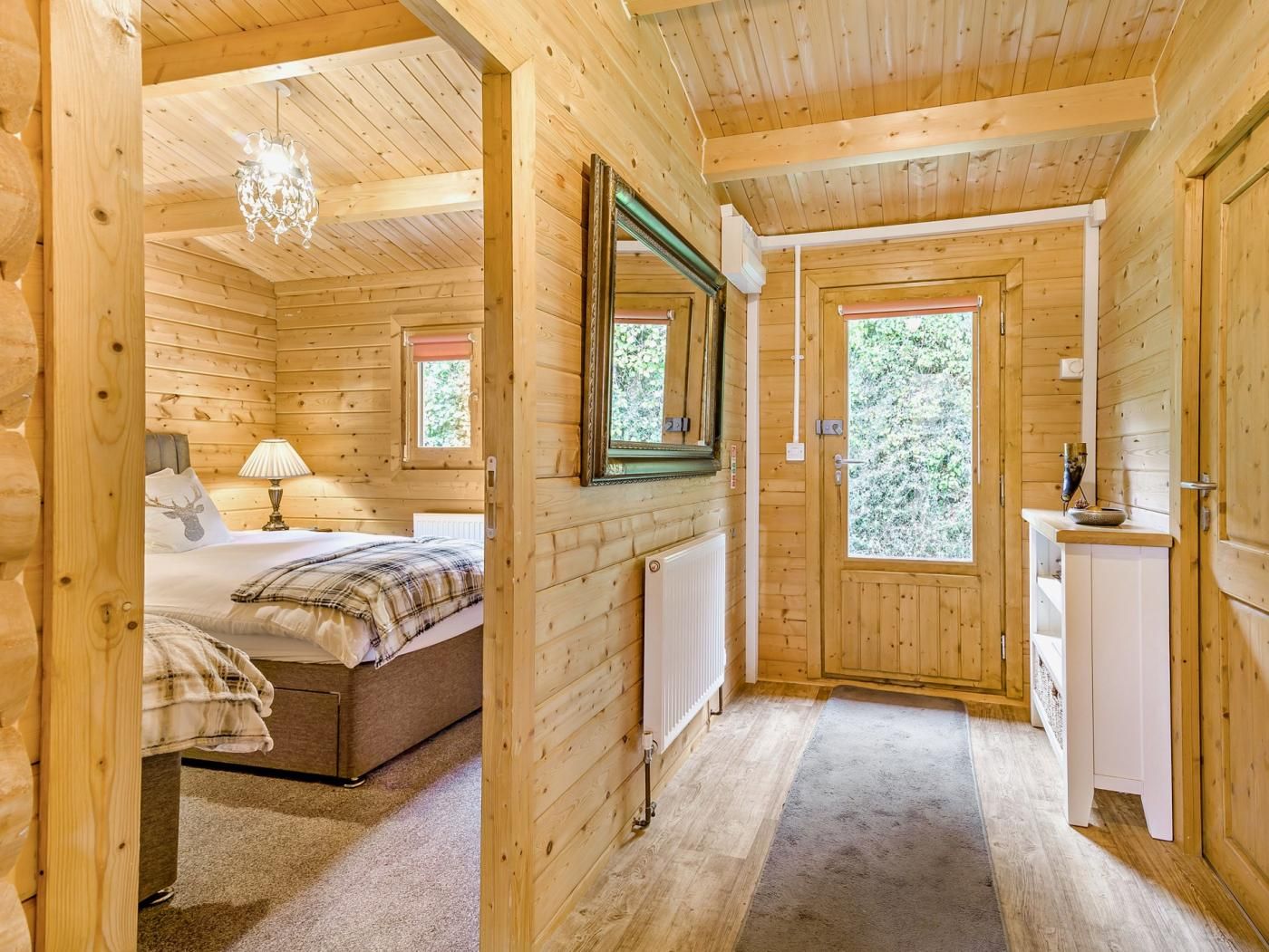 A wooden cabin interior with a bedroom, a bathroom, and a hallway.