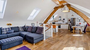 A loft-style living space with a large sectional sofa, a dining area, and a kitchen. - 1 Bed in Inverkeithing (oc-96221) (Inverkeithing)