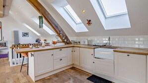 A modern kitchen with skylights, white cabinets, and a wooden countertop. - 1 Bed in Inverkeithing (oc-96221) (Inverkeithing)