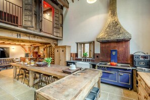 Eine rustikale Küche mit einem großen Herd, Holzschränken und einem Essbereich mit einem langen Tisch.