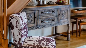 Una scala in legno conduce a una zona pranzo con un comò dallo stile vintage e una sedia a fantasia.