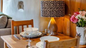 Un tavolo da pranzo in legno apparecchiato con piatti, bicchieri, posate e una lampada con un paralume a fantasia leopardata.