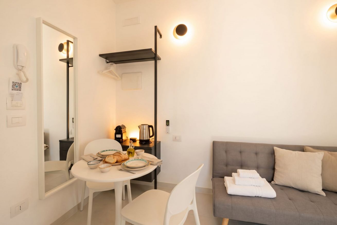 Un espace de vie compact comprenant un coin cuisine, un coin repas et un canapé avec des serviettes.