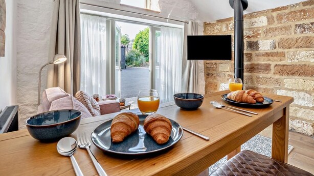 Een ontbijt met croissants, sinaasappelsap en een kom op een houten tafel.