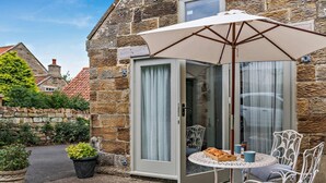 Een stenen gebouw met een patio, compleet met een tafel, stoelen en een parasol.