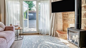 Een gezellige woonkamer met een bank, een flatscreen televisie, een open haard en uitzicht door de glazen deuren.