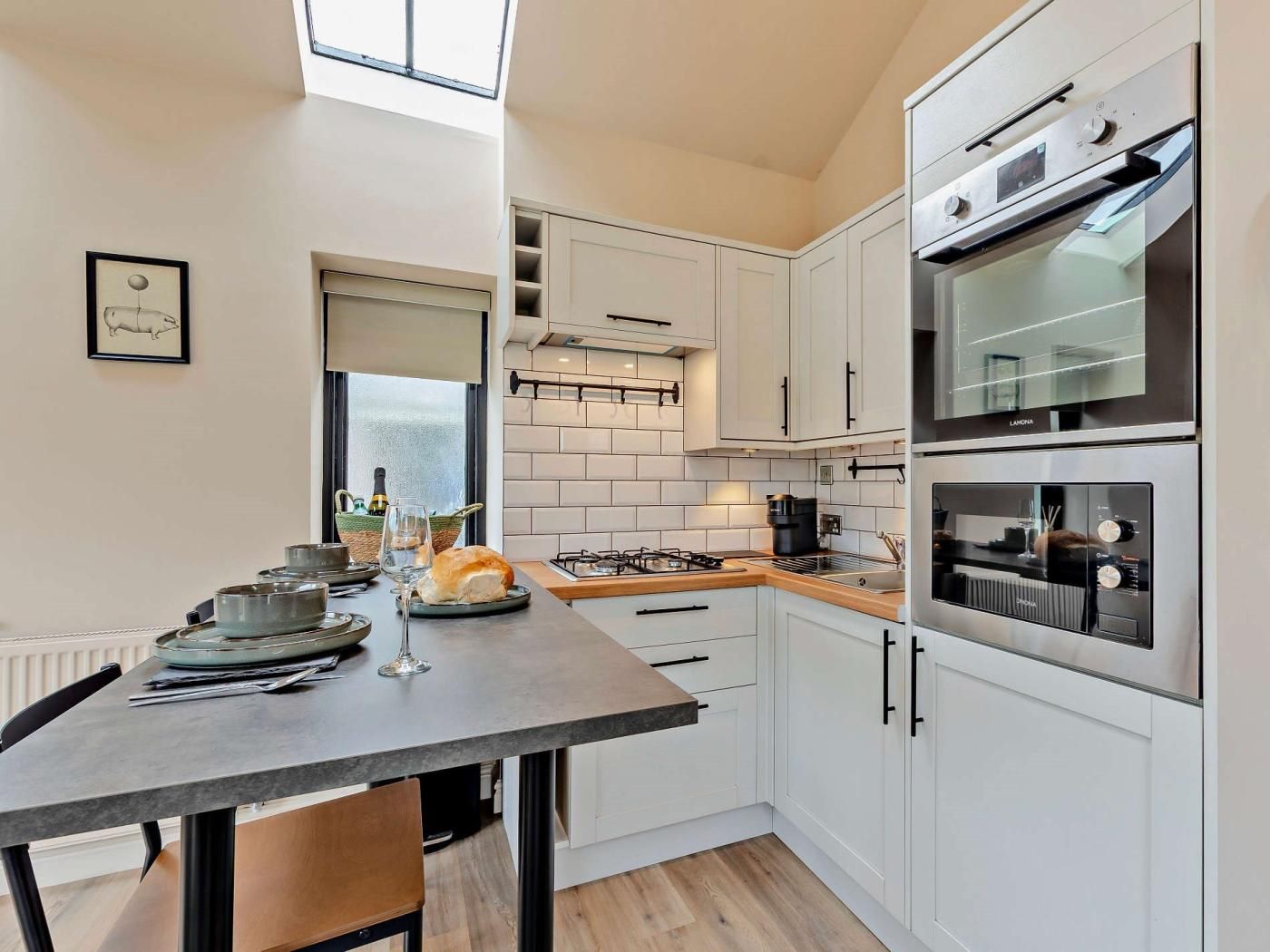 A modern kitchen with white cabinets, a gas stove, and a built-in oven.