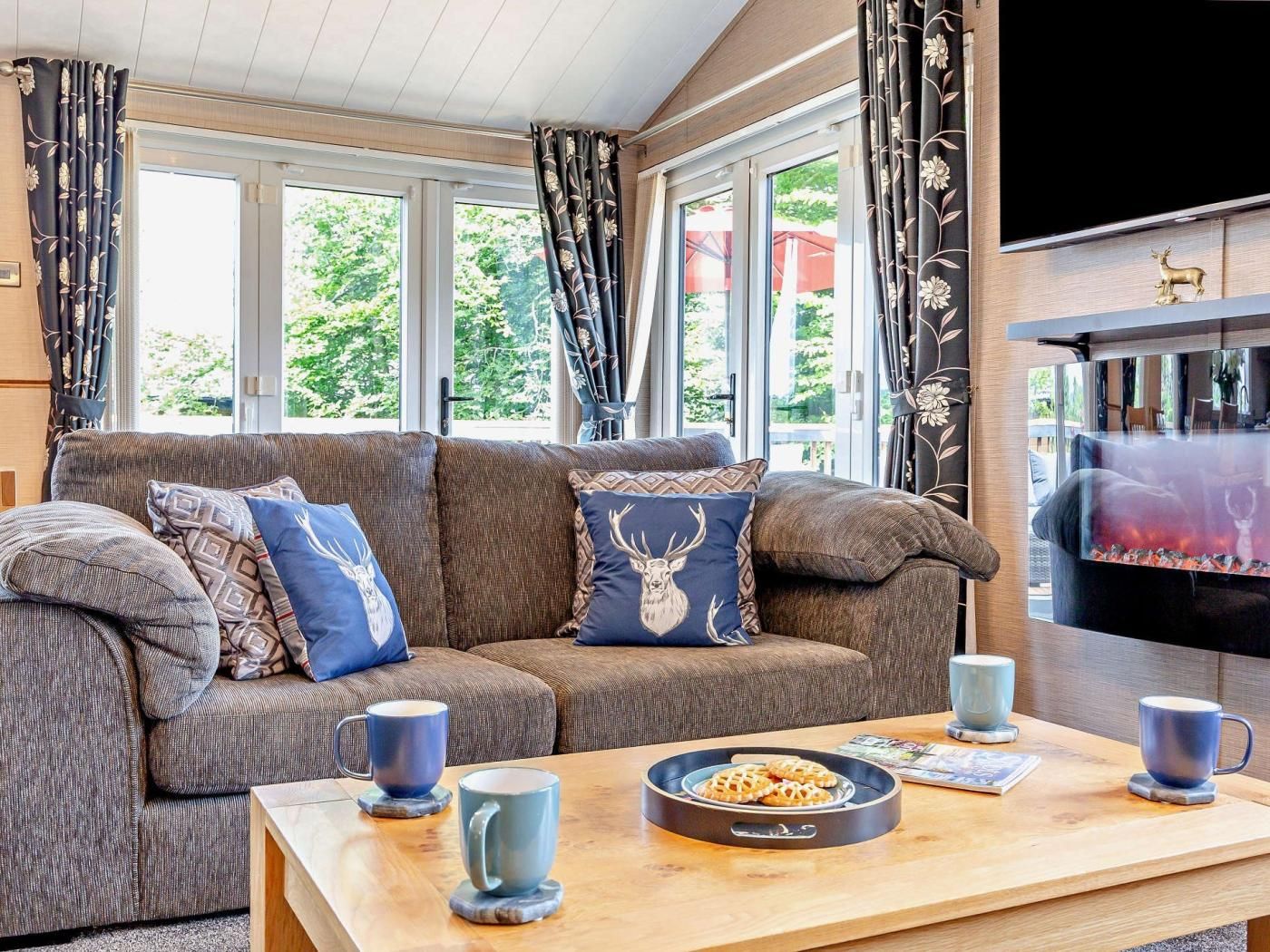 A cozy living room with a sofa, decorative pillows, a coffee table with pastries, and a fireplace.