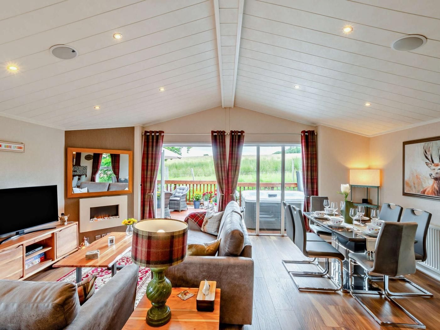 A spacious living area with a television, sofa, dining table, and a view of the outdoors.