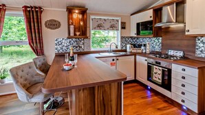 A modern kitchen with a wooden island, stainless steel appliances, and a view of greenery outside.