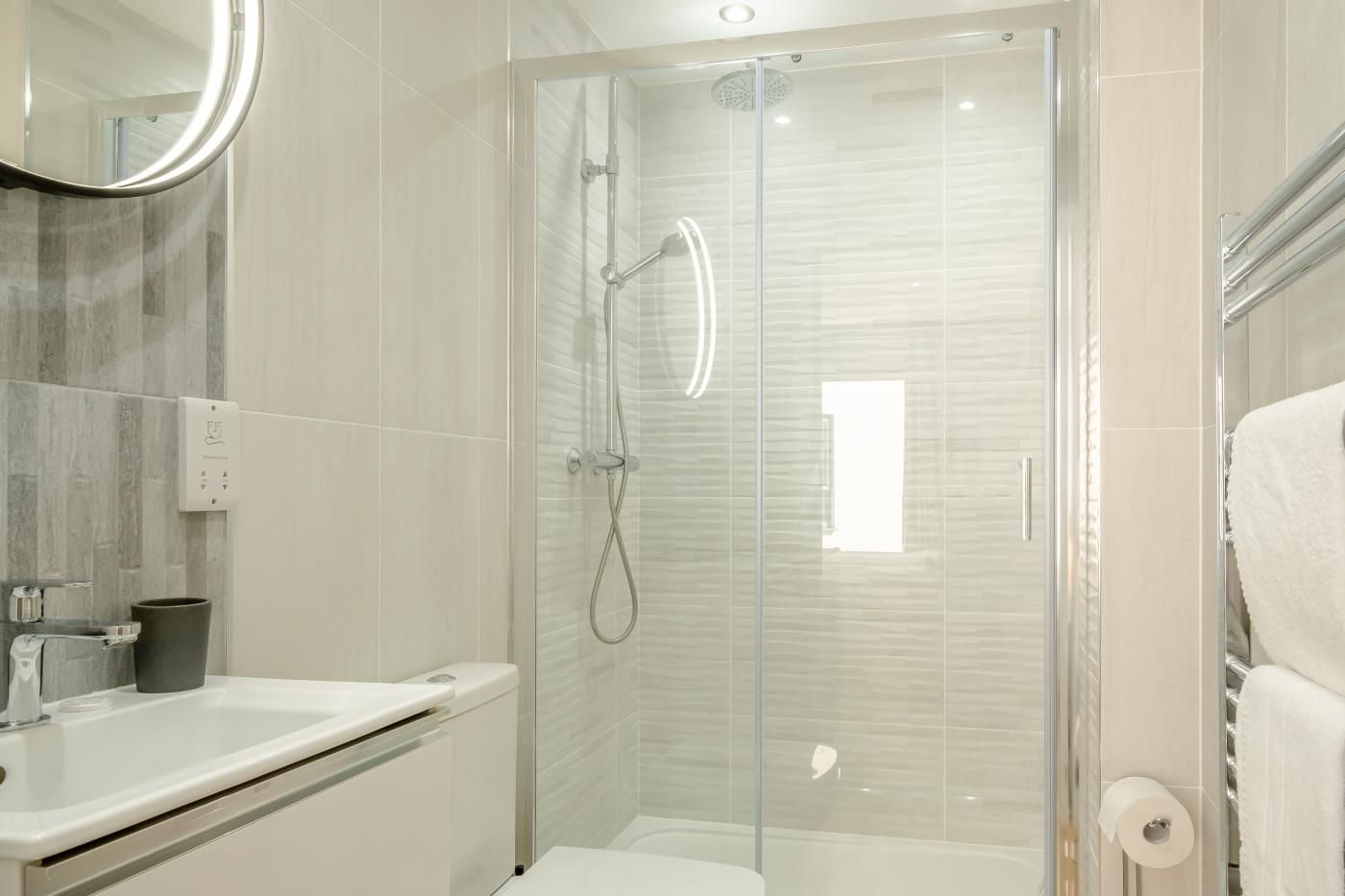 A modern bathroom with a glass-enclosed shower, a white sink, and a toilet.