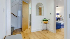Eine Treppe führt zu einer Zwischenebene, an der Wand hängt ein Spiegel und ein kleiner Tisch mit einer Pflanze steht daneben.