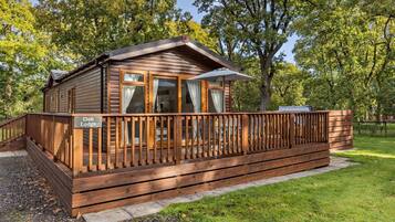 Un chalet en bois doté d’une terrasse, d’un patio couvert et d’une enseigne indiquant « Oak Lodge ».