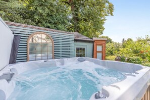 Ein Whirlpool mit Holzterrasse und einem kleinen Gebäude mit Fenster und Tür.