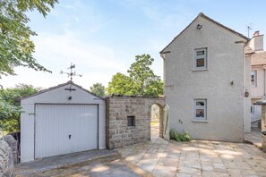 Ein zweistöckiges Gebäude mit einer Fassade aus Stein, eine Garage mit weißer Tür und ein steinerner Bogen, der zum Eingang führt.